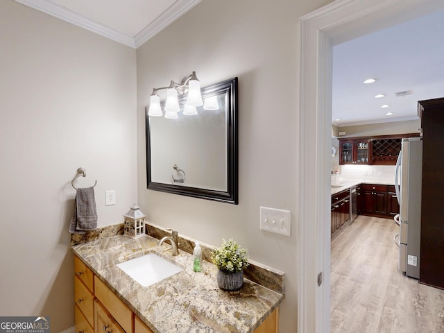 bathroom with recessed lighting, ornamental molding, wood finished floors, and vanity