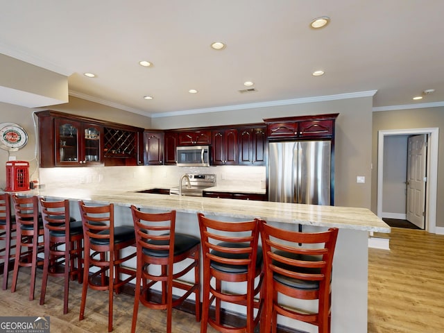 kitchen featuring visible vents, backsplash, appliances with stainless steel finishes, light wood-style floors, and dark brown cabinets