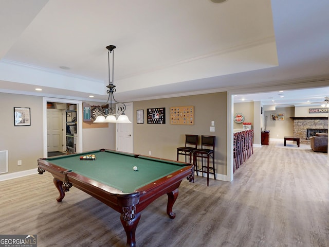 playroom with ornamental molding, a tray ceiling, baseboards, and wood finished floors