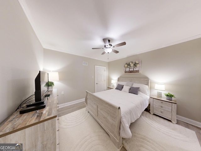 bedroom with light wood finished floors, visible vents, baseboards, and ornamental molding