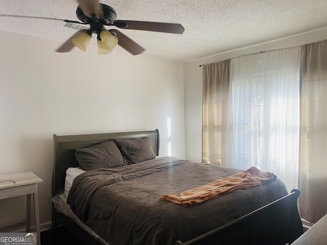 bedroom with ceiling fan and a textured ceiling