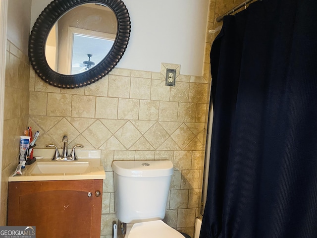 bathroom with tile walls, vanity, toilet, and a shower with shower curtain