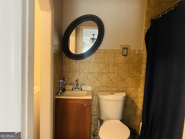 bathroom featuring vanity, tile walls, and toilet