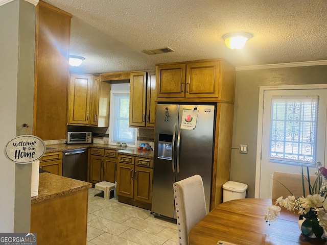 kitchen featuring appliances with stainless steel finishes, a textured ceiling, and dark stone countertops