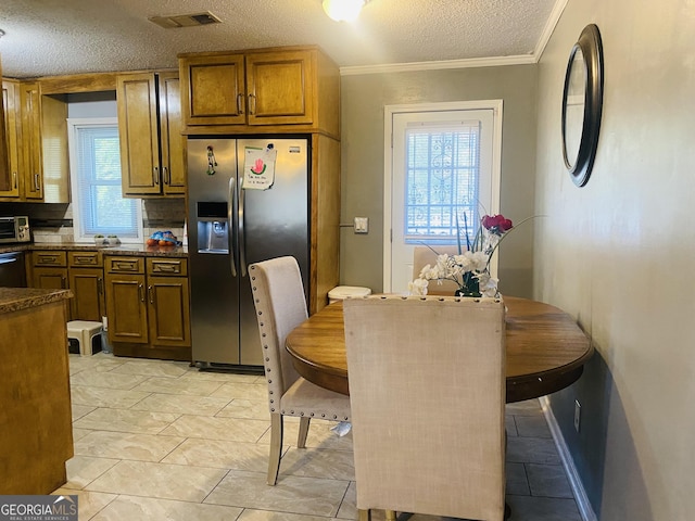 kitchen with dishwasher, stainless steel refrigerator with ice dispenser, ornamental molding, a textured ceiling, and dark stone counters