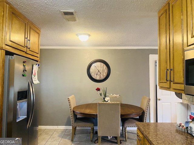 dining area with crown molding, a textured ceiling, and light tile patterned flooring