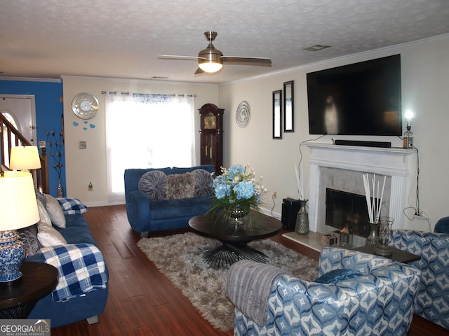 living room with crown molding, a premium fireplace, ceiling fan, a textured ceiling, and dark hardwood / wood-style flooring