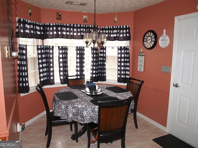 dining area with an inviting chandelier, tile patterned floors, and a textured ceiling