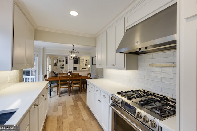 kitchen featuring white cabinetry, hanging light fixtures, crown molding, and gas stove