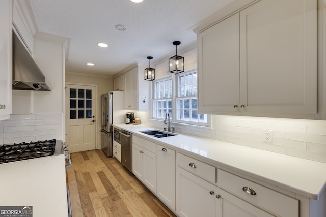 kitchen with white cabinets, appliances with stainless steel finishes, sink, and wall chimney range hood