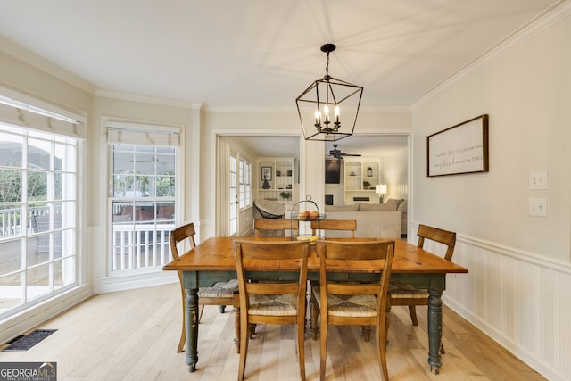 dining area with light hardwood / wood-style flooring, ornamental molding, and a chandelier