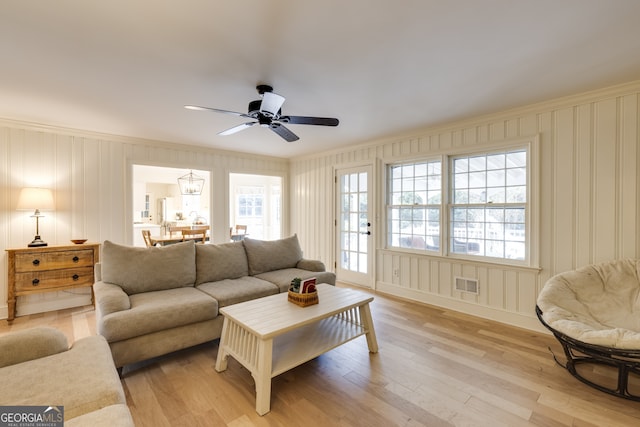 living room with ceiling fan, ornamental molding, and light hardwood / wood-style flooring