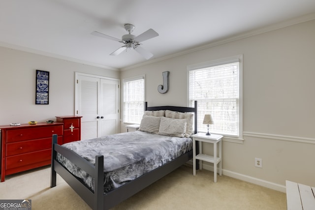 carpeted bedroom with ornamental molding, ceiling fan, and a closet