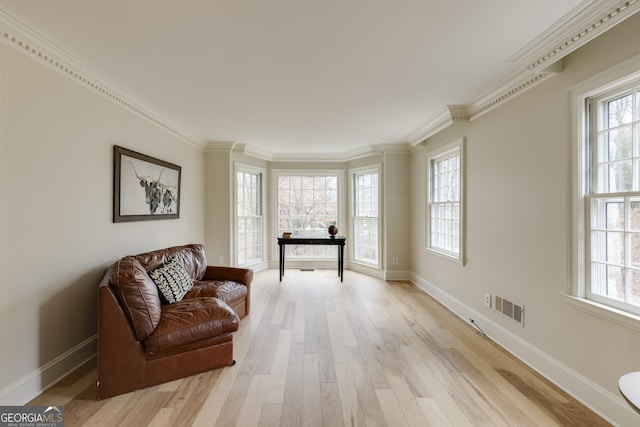 sitting room featuring crown molding, a healthy amount of sunlight, and light wood-type flooring