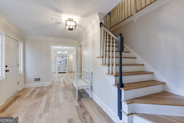 entrance foyer featuring an inviting chandelier, light hardwood / wood-style flooring, and ornamental molding