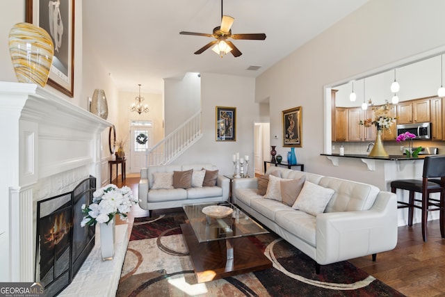 living room with ceiling fan with notable chandelier, a tile fireplace, and hardwood / wood-style floors