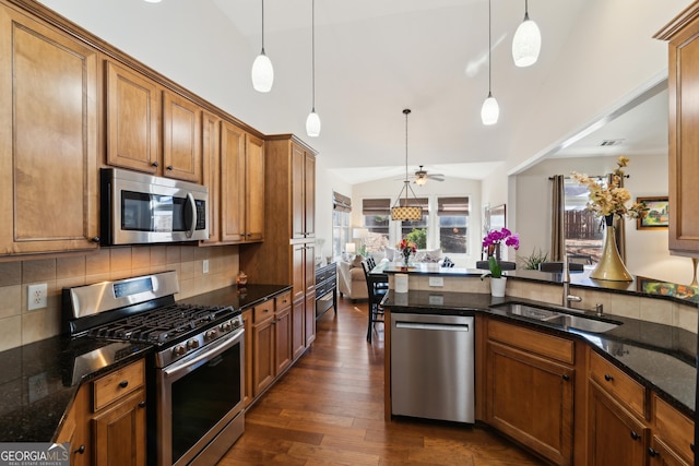 kitchen with sink, lofted ceiling, hanging light fixtures, and stainless steel appliances