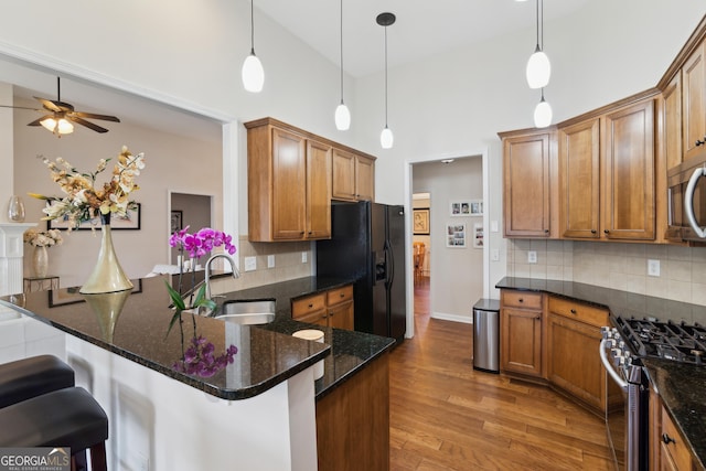 kitchen with appliances with stainless steel finishes, sink, pendant lighting, and kitchen peninsula