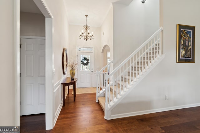 entrance foyer featuring dark hardwood / wood-style flooring, a high ceiling, and an inviting chandelier