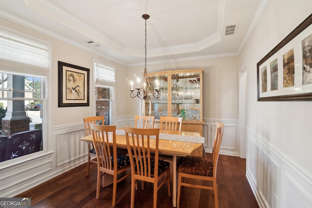 dining space with crown molding, a chandelier, a tray ceiling, and dark wood-type flooring