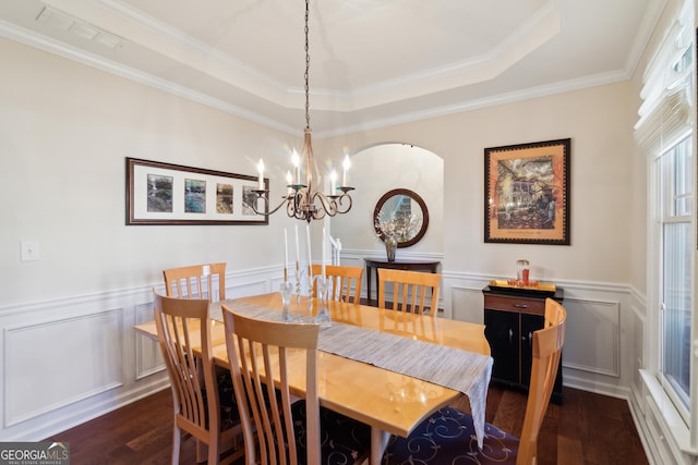 dining room with a raised ceiling, an inviting chandelier, dark wood-type flooring, and ornamental molding