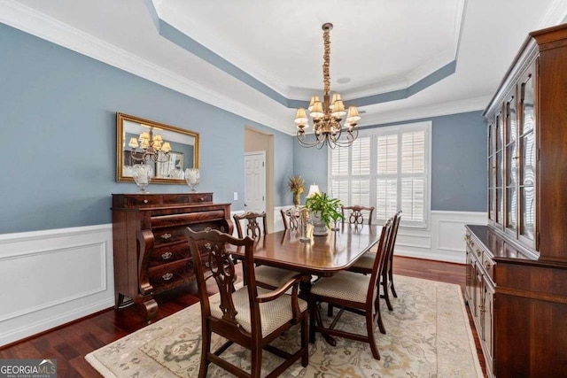 dining room featuring a raised ceiling, ornamental molding, hardwood / wood-style flooring, and a chandelier