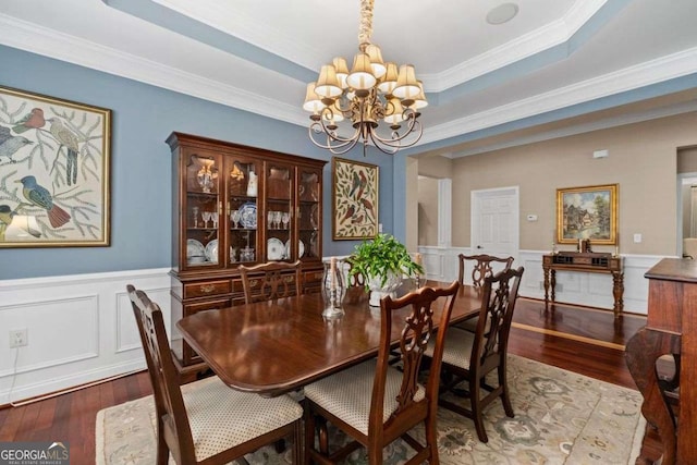 dining room with an inviting chandelier, a tray ceiling, dark hardwood / wood-style flooring, and crown molding