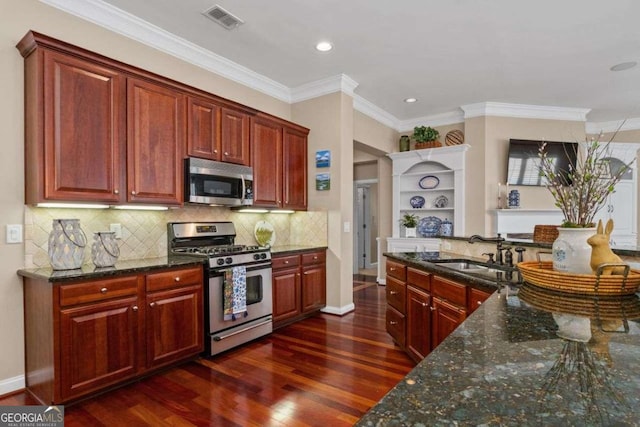 kitchen with appliances with stainless steel finishes, tasteful backsplash, sink, dark hardwood / wood-style flooring, and dark stone counters