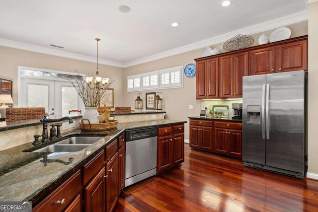 kitchen with sink, dark wood-type flooring, appliances with stainless steel finishes, a wealth of natural light, and dark stone counters