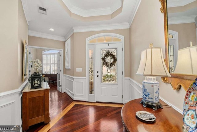 foyer with dark wood-type flooring, crown molding, and a raised ceiling