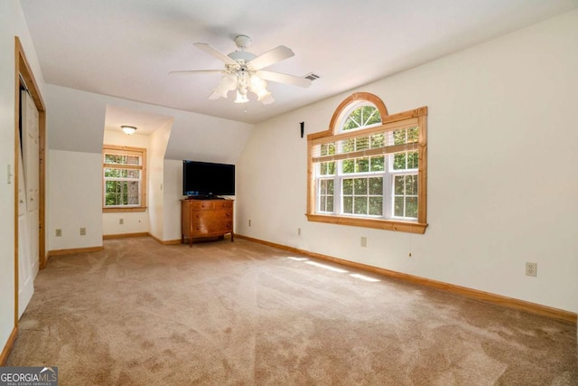 unfurnished living room featuring ceiling fan, baseboards, visible vents, carpet floors, and lofted ceiling