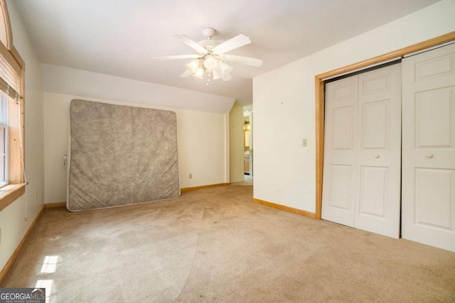 unfurnished bedroom featuring light colored carpet, a ceiling fan, a closet, and baseboards