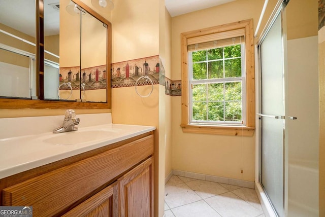 bathroom with baseboards, vanity, a shower with shower door, and tile patterned floors