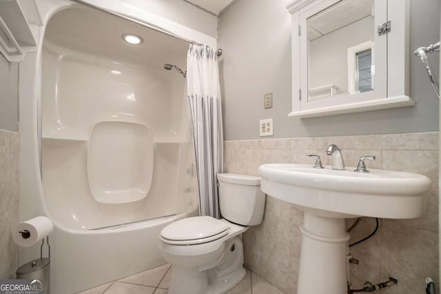 bathroom featuring shower / tub combo, tile walls, toilet, tile patterned floors, and a wainscoted wall