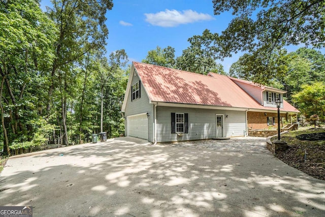 view of side of property with metal roof, brick siding, and a garage