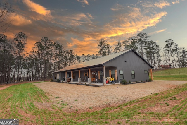 back house at dusk featuring a lawn