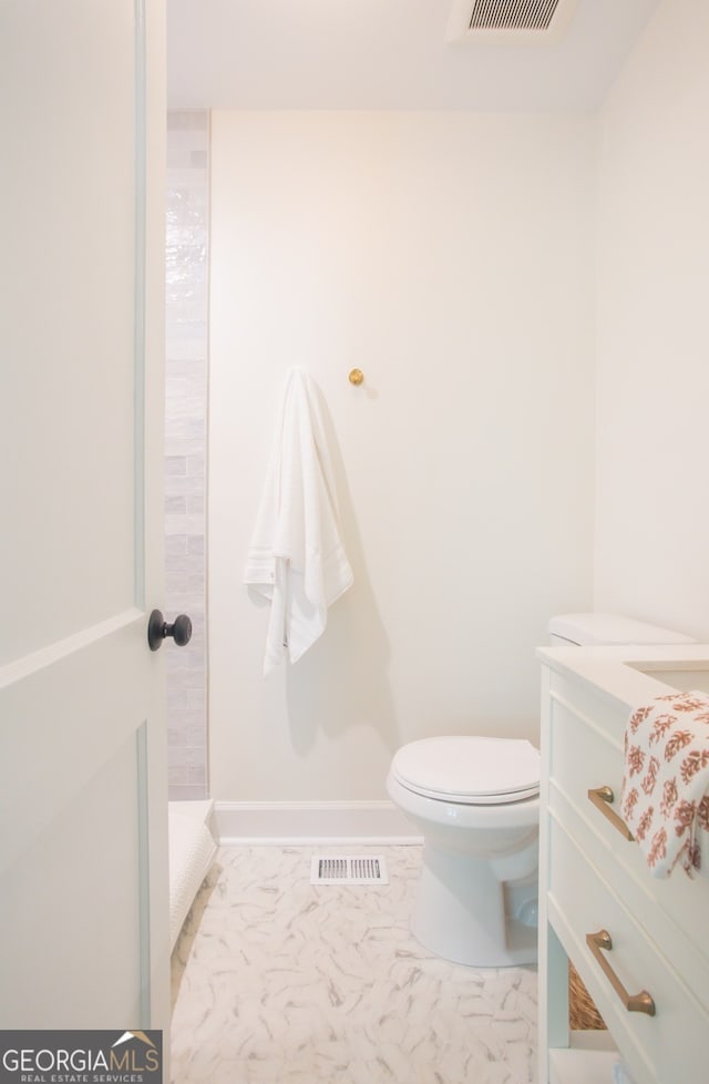 bathroom featuring toilet, vanity, and walk in shower