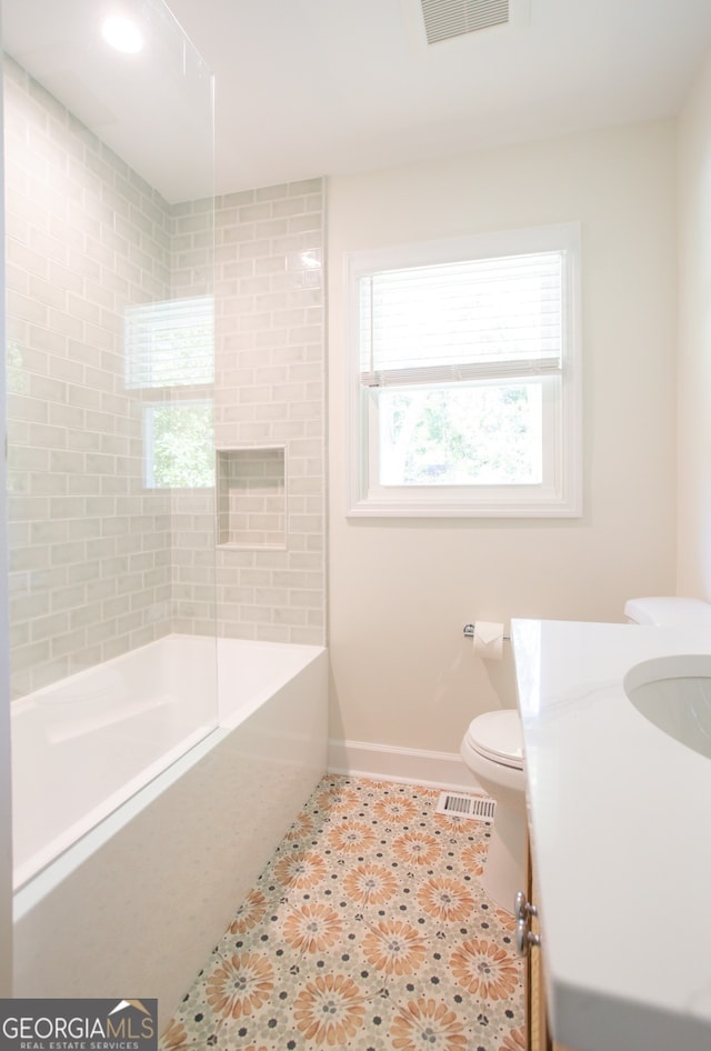 full bathroom with tile patterned flooring, vanity, tiled shower / bath combo, and toilet