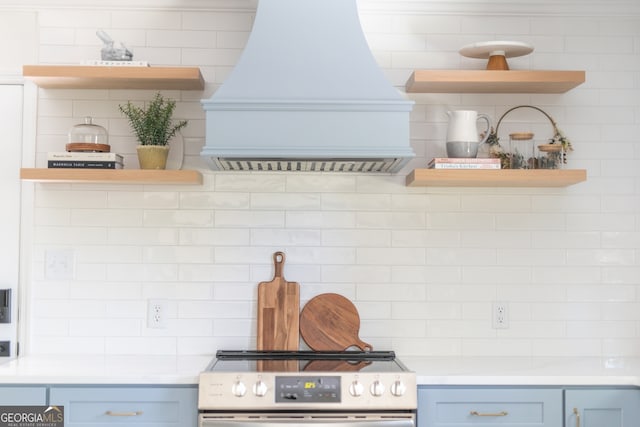 kitchen featuring premium range hood, blue cabinets, tasteful backsplash, and electric range