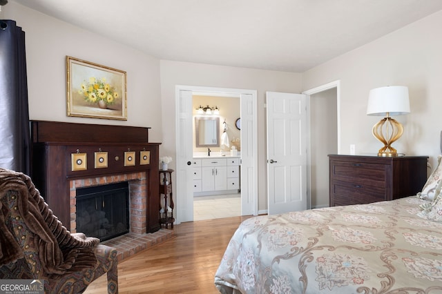 bedroom featuring connected bathroom, a fireplace, and light hardwood / wood-style floors