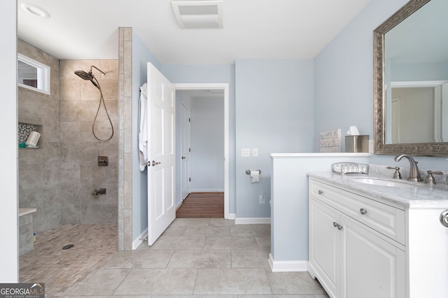 bathroom with tile patterned flooring, vanity, and tiled shower