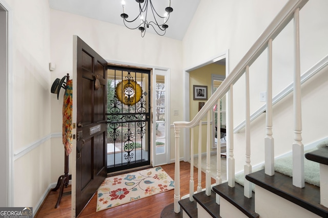 entryway with vaulted ceiling, hardwood / wood-style floors, and a notable chandelier