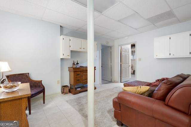 living room with a paneled ceiling and light tile patterned floors