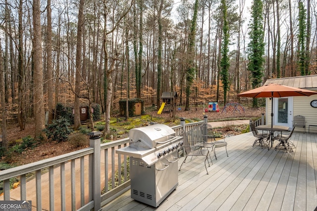 wooden deck featuring a playground and area for grilling