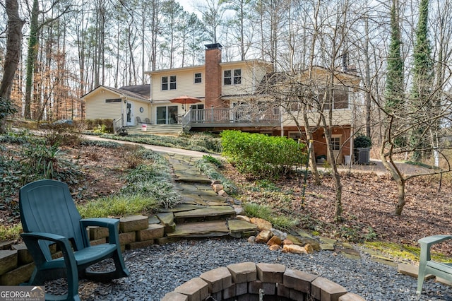 back of house featuring a deck and a fire pit