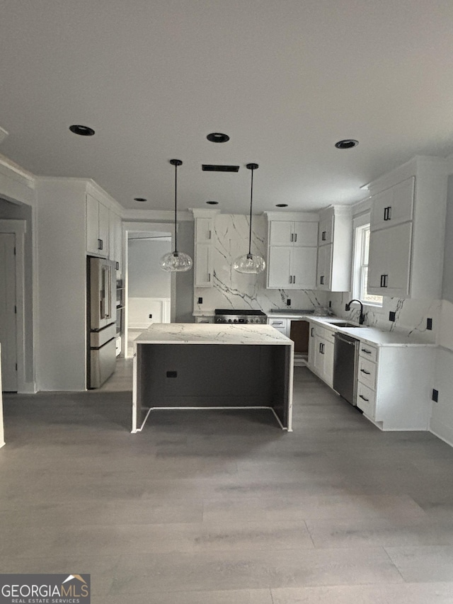 kitchen featuring white cabinetry, appliances with stainless steel finishes, a kitchen island, and hanging light fixtures