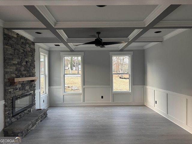 unfurnished living room featuring beamed ceiling, wood-type flooring, and a stone fireplace