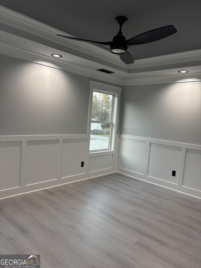 empty room featuring ornamental molding, ceiling fan, light hardwood / wood-style floors, and a tray ceiling