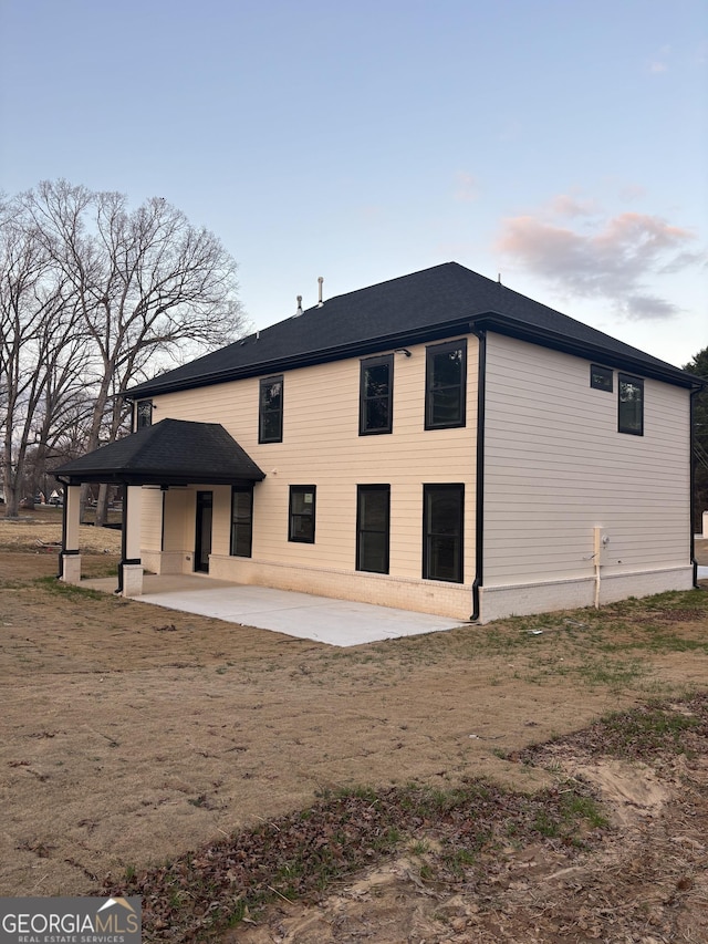 back house at dusk featuring a patio