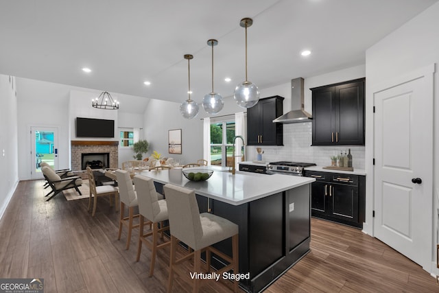 133 Old Alabama Rd SE, Emerson, GA 30137 - kitchen featuring wall chimney range hood, dark cabinetry, a kitchen breakfast bar, stainless steel gas stove, and light countertops